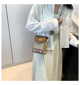 Borsa a tracolla chic in tela marrone e beige con ampia tracolla jacquard indossata