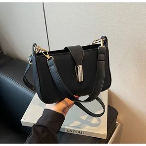 Detail of black matte shoulder bag with gold clasp and dual detachable straps