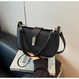 Detail of black matte leather shoulder bag with a cylindrical gold metallic buckle
