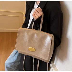 Detail of vintage brown leather shoulder bag with gold logo plaque and flap closure