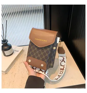 Dettaglio borsa porta cellulare vintage in pelle marrone e tela con monogramma e borchie
