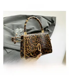 Detail of leopard print handbag with golden U-shaped buckle and round handle
