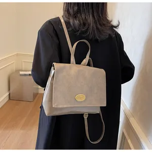 Detail of vintage beige PU leather backpack with gold emblem and thin shoulder straps