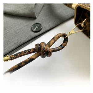 Detail view of leopard print bag strap with stylish knot and gold metal hook buckles