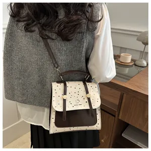 Detail of cream and brown crossbody bag with colorful dots and logo in a cozy setting