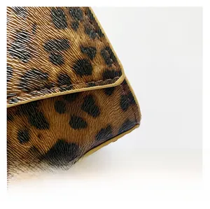 Detailed macro view of leopard print leather texture with brown stitched edge