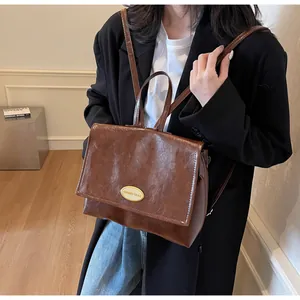 Detail view of a vintage brown oil-wax leather backpack with gold metal hardware