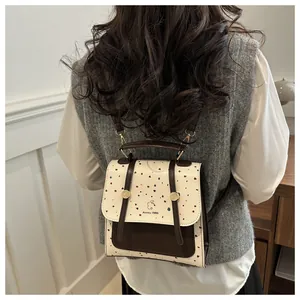 Detailed back view of a cream polka dot backpack with brown straps worn by a model