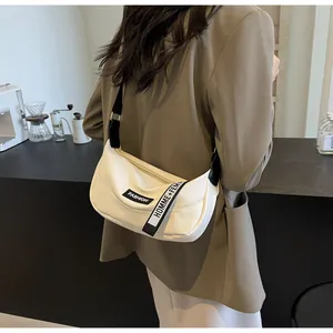 Dettaglio borsa a mezzaluna crema con trama litchi e tracolla con logo fashion
