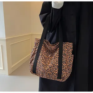 Detail of leopard print canvas tote bag featuring side pocket and wide black straps