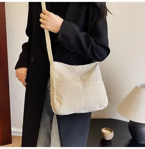 Detailed texture of corduroy crossbody bag with large pocket shown on a model