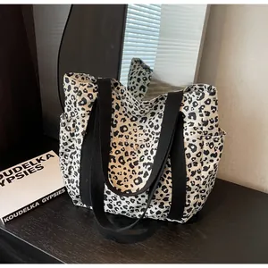 Detail of canvas tote bag featuring black and white leopard print and functional side pockets