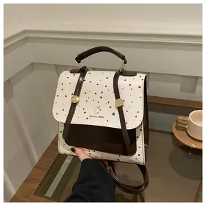 Detailed shot of white polka dot backpack with brown leather straps and bunny logo