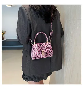 Pink leopard print crossbody bag with gold buckle shown on a model in a grey blazer