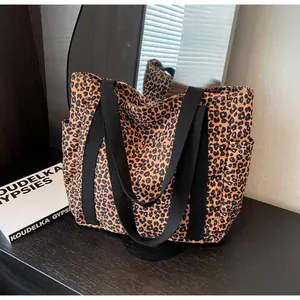 Close-up of leopard print canvas tote bag with side pockets and black web handles