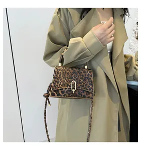 Detail of trendy leopard print handbag with gold U-shaped buckle on khaki trench coat