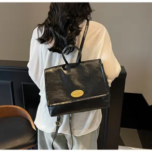 Model wearing a black leather vintage backpack with gold metal logo and flap design