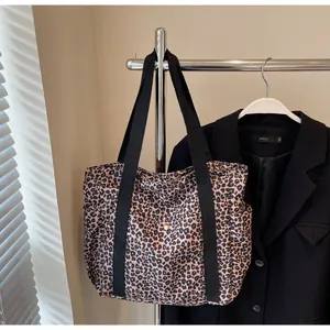 Detail of leopard print canvas tote bag with black strap and metallic button closure