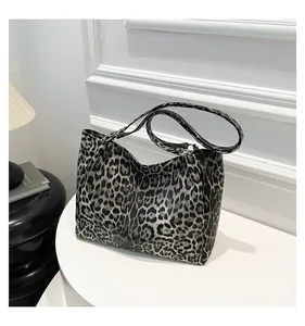Detail of grey leopard print tote bag with slim shoulder strap on a white stand