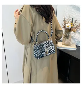 Detailed view of the leopard print handbag featuring a golden arch metal lock and top handle