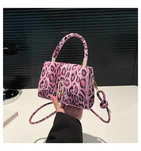 Pink leopard print square bag with gold buckle and knotted strap held by hand