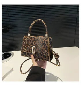 Detailed view of leopard print square bag featuring gold clasp and textured leather