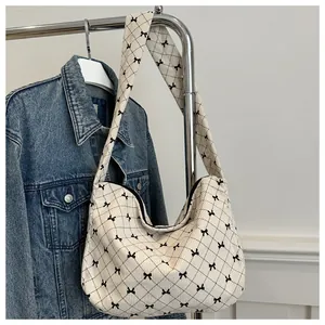 Detail der cremefarbenen Cord-Hobo-Tasche mit schwarzen Schleifen und Steppmuster