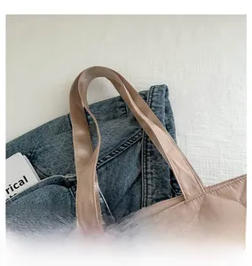 Détail d'un cabas rose en nylon matelassé avec de larges anses sur fond de denim