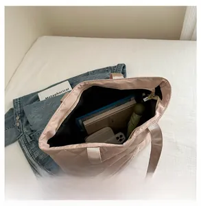 Intérieur spacieux du sac cabas rose matelassé avec des livres et un parapluie