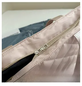 Détail de la fermeture éclair argentée et du tissu satiné rose matelassé