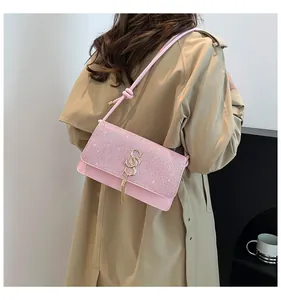 Détail du sac à bandoulière rose pailleté avec pompon doré et boucle en métal chic