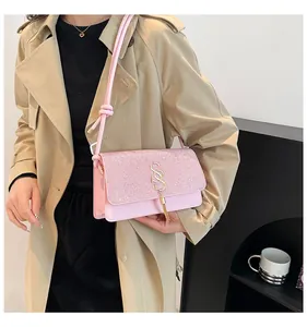 Détail du sac rose avec rabat à paillettes, logo S doré et gland métallique élégant