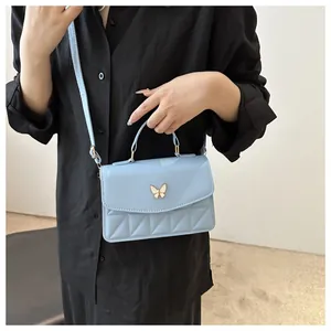 Detail van lichtblauwe crossbodytas met gouden vlindersluiting en gewatteerd patroon