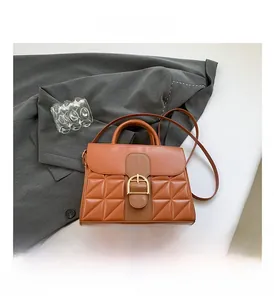 Detailed macro view of caramel orange faux leather bag with diamond quilted pattern and gold buckle