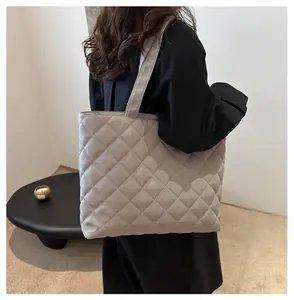 Détail du sac fourre-tout matelassé beige avec large bandoulière porté par un mannequin