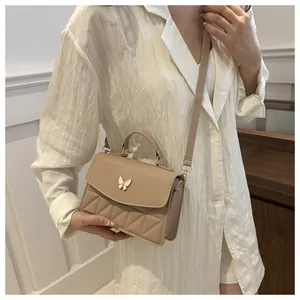 Detail van beige gewatteerde crossbody tas met witte vlinder en een bovenhandvat