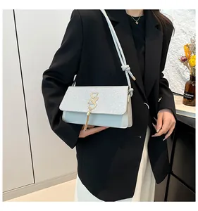 Détail du sac en cuir bleu avec rabat à paillettes argentées et gland métallique sur mannequin