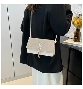 Détail du sac bandoulière à paillettes dorées avec logo SS et pampilles à franges