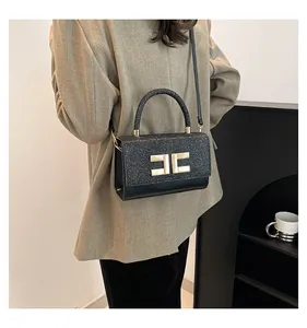 Detail der eleganten schwarzen Pailletten-Lederhandtasche mit goldener Schließe am Model