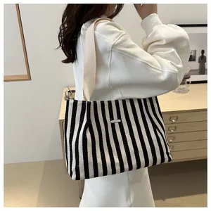 Détail d'un sac cabas en toile rayée avec boucle métallique et bandoulière en sangle beige