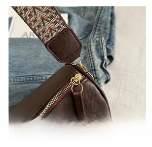 Detail of smooth gold zipper on brown pebbled leather bag with ethnic woven strap