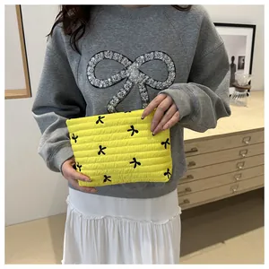 Gelbe gesteppte Kosmetiktasche mit schwarzen Schleifen, präsentiert von einem Model
