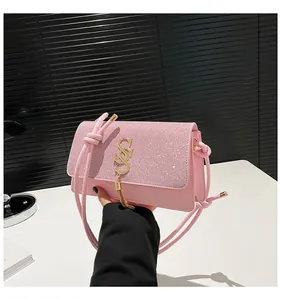 Détail du sac bandoulière rose pailleté avec logo doré et pompon élégant pour femme
