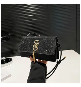 Détail du sac à main noir avec sequins scintillants et logo à pompon en métal doré