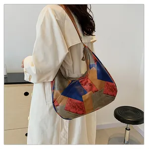 Dettaglio della borsa tote color-block con patchwork geometrico in pelle indossata su trench