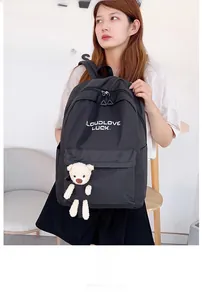 Détail d'un sac à dos en nylon noir avec broderie blanche et charmant petit ours en peluche
