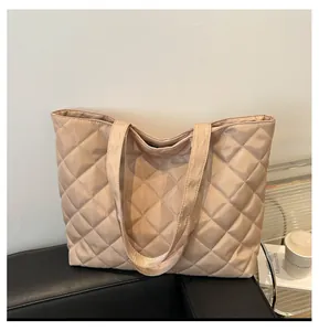 Sac fourre-tout matelassé kaki en nylon brillant posé sur un siège en cuir
