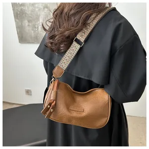 Detail of brown faux leather pillow bag with wide geometric woven shoulder strap