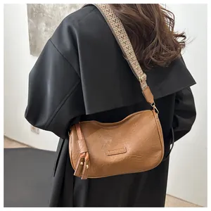 Brown leather pillow bag with wide geometric woven strap shown on model's shoulder