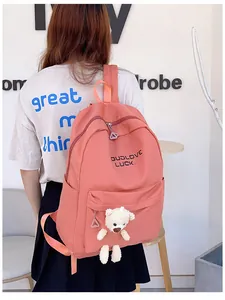 Détail du sac à dos en nylon rose avec un ours en peluche et broderie minimaliste
